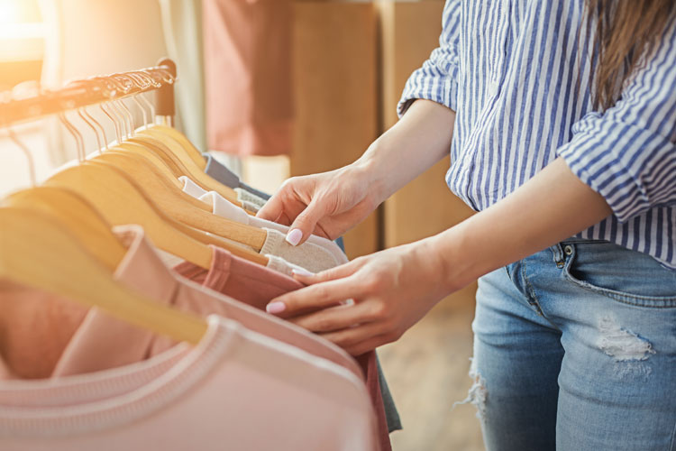 frau durchsucht kleidung an kleiderstange