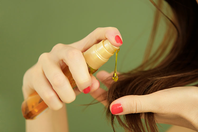 frau macht sich haaröl auf die haarspitzen