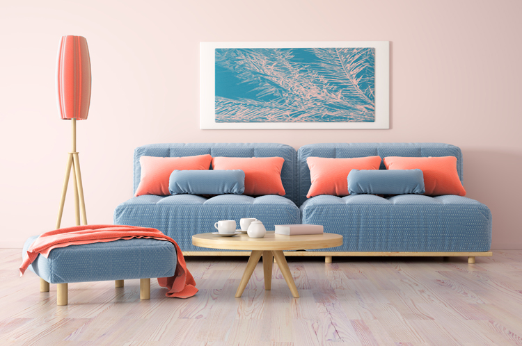 blaue couch im hellen wohnzimmer mit kissen, decke und stehlampe in der trendfarbe living coral