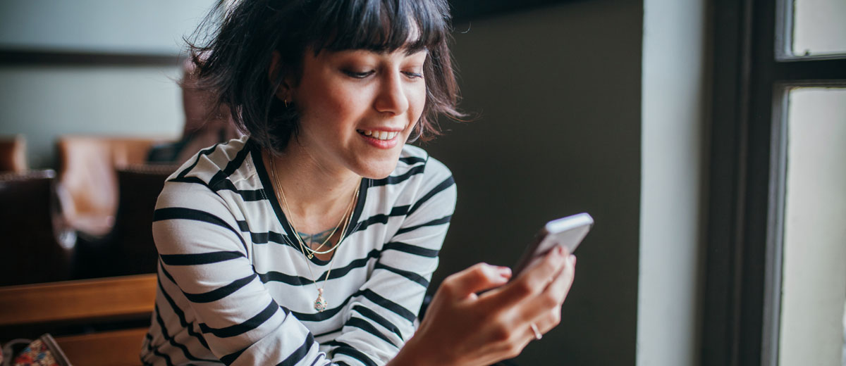 lächelnde frau mit handy im café