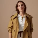 Model vor beigem Hintergrund trägt Trenchcoat