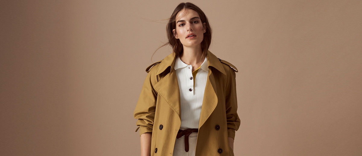 Model vor beigem Hintergrund trägt Trenchcoat