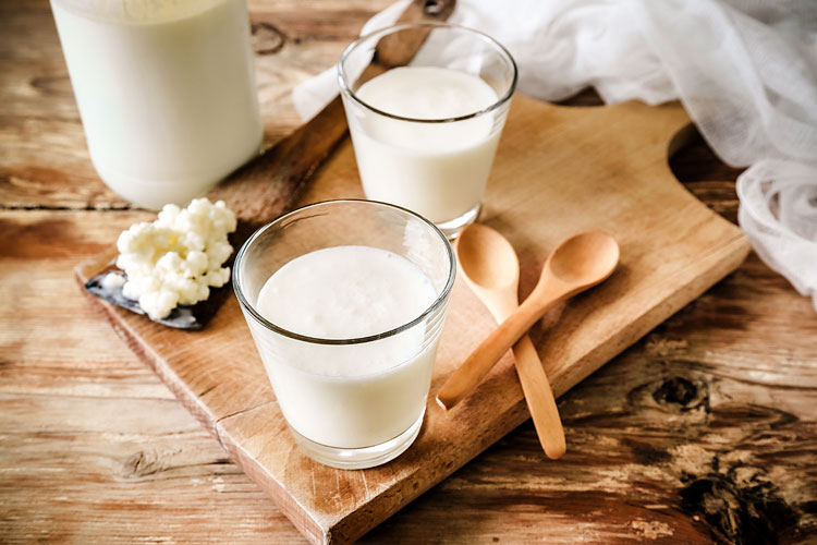 kefir und körniger frischkäse auf einem holzbrett auf einem holztisch