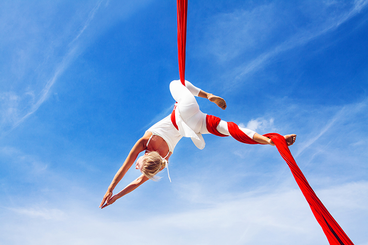 frau vor blauem himmel trainiert aerial yoga