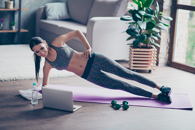 frau macht workout zuhause vor dem laptop