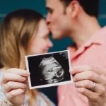 pärchen mit ultraschallbild ihres babys in der hand