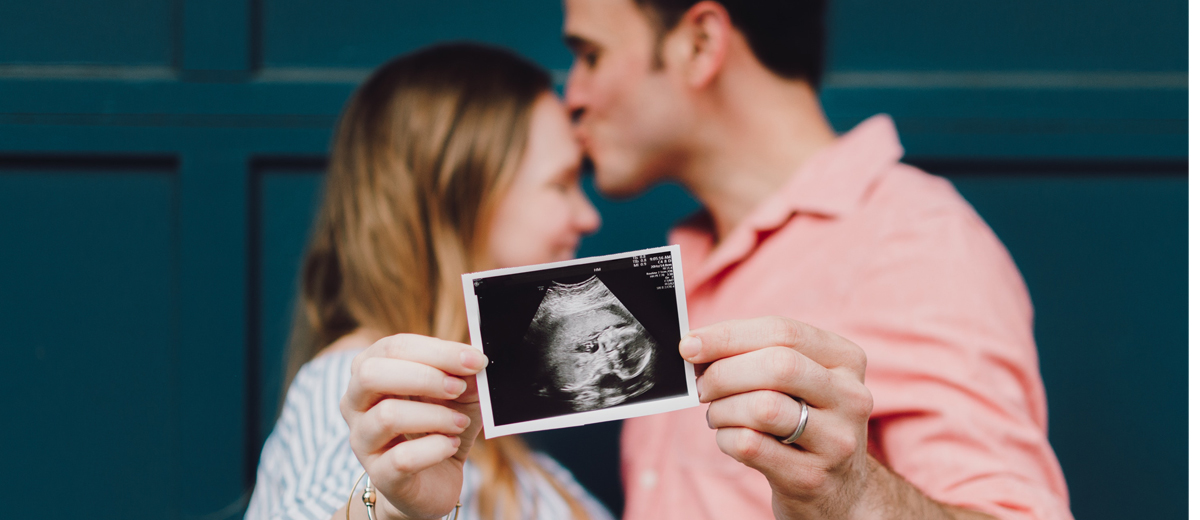 pärchen mit ultraschallbild ihres babys in der hand