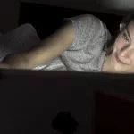 junge frau liegt im bett und schaut auf dem laptop einen film