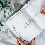 Frauenhand trägt Termine in Kalender ein