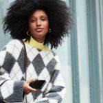 Frau mit Afrolocken trägt Trend-Pullover mit Argyle-Muster