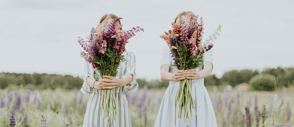 zwei frauen auf einer wiese mit blumensträußen in den händen